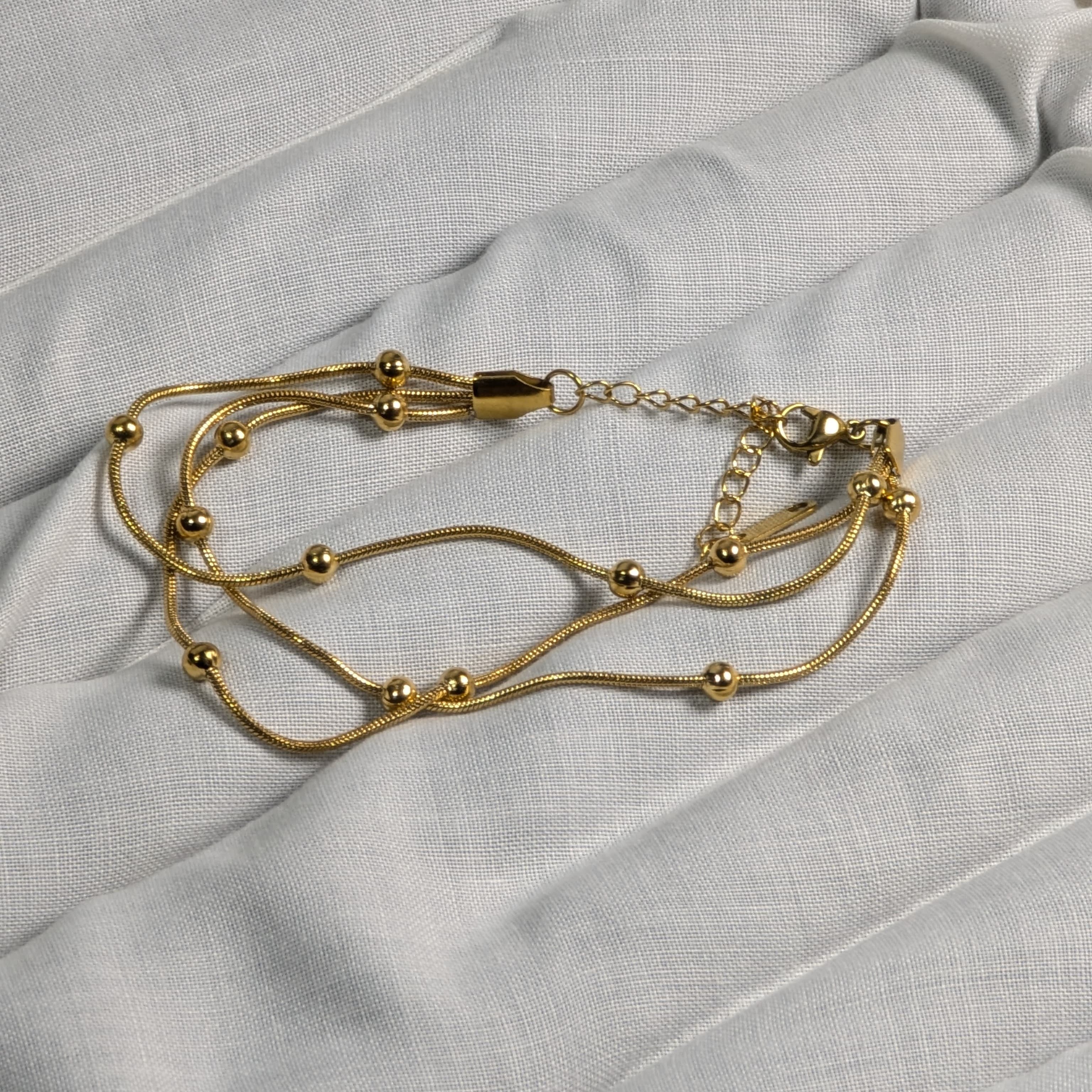 Gold bracelet on a light gray fabric background
