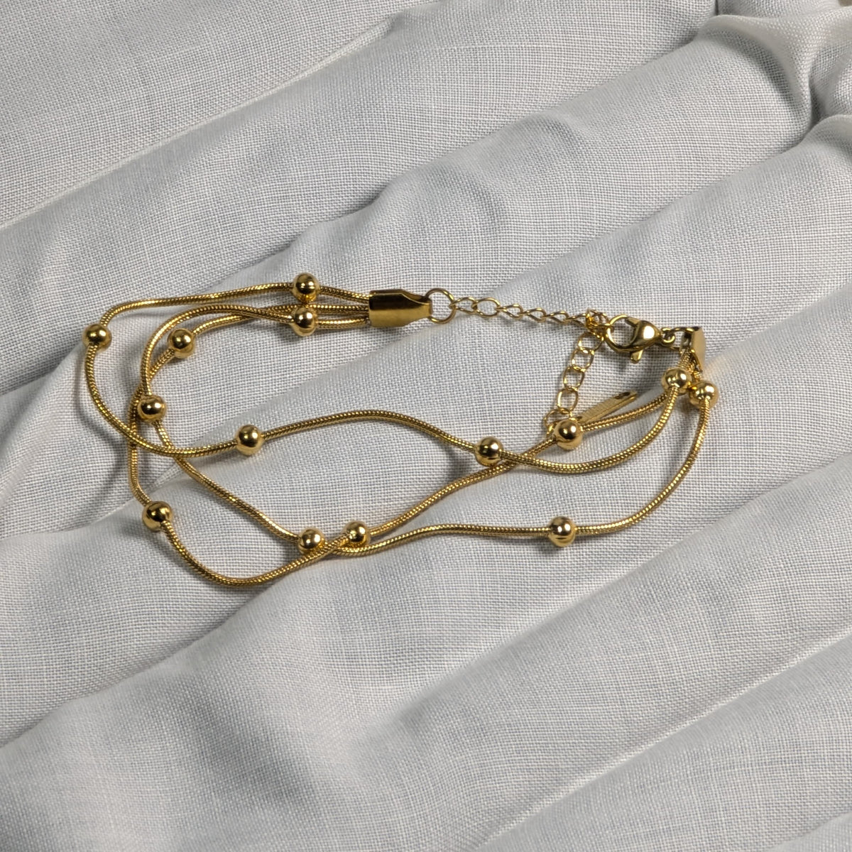 Gold bracelet on a light gray fabric background