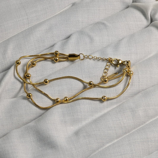 Gold bracelet on a light gray fabric background