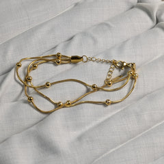 Gold bracelet on a light gray fabric background