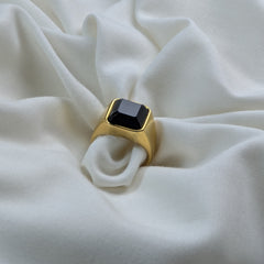 Gold ring with a black gemstone on a white fabric background