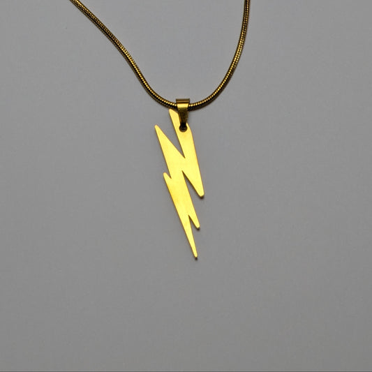 Gold necklace with a yellow lightning bolt pendant on a gray background