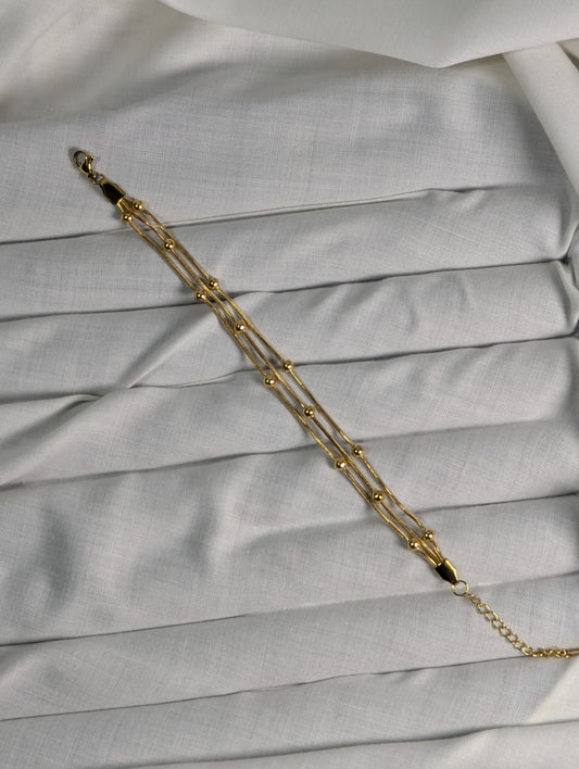 Gold chain bracelet on a light gray fabric background