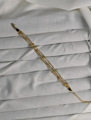 Gold chain bracelet on a light gray fabric background