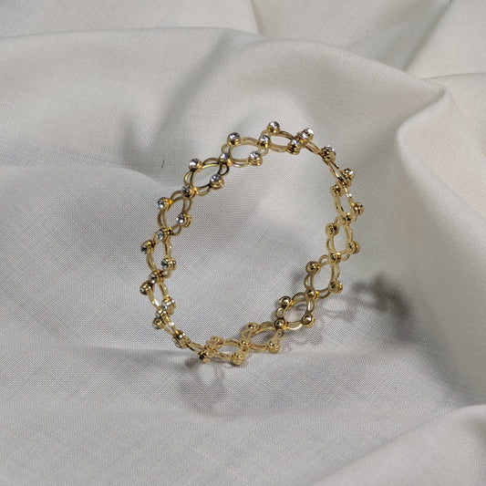 Gold bracelet on a white fabric background