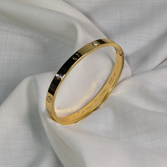 Gold bracelet with engraved text on a light fabric background