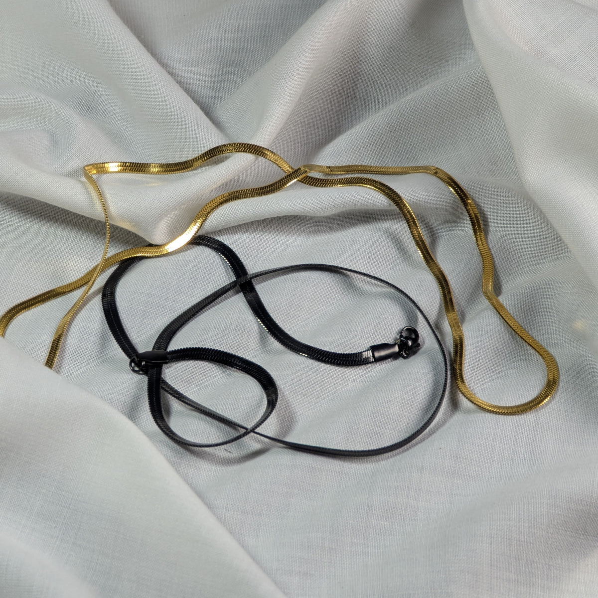 Gold and black necklace on a white fabric background
