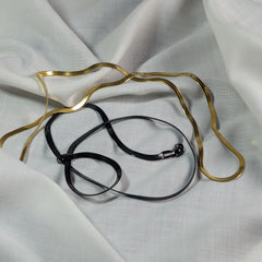 Gold and black necklace on a white fabric background